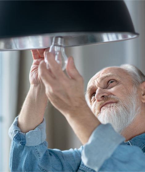 elderly man changing a lightbulb in home