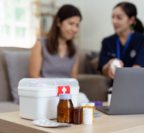 nurse visiting elderly patient at home with medications on table